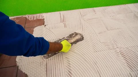 Worker Spreading Tile Mortar Beside Newly Laid Ceramic Tiles Stock Photos