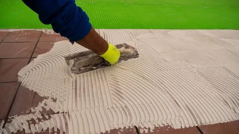Worker Spreading Tile Mortar Beside Newly Laid Ceramic Tiles 库存照片