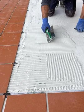 Worker Spreading Tile Mortar Beside Newly Laid Ceramic Tiles Stock Photos