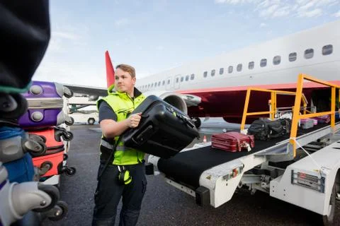 Worker Stacking Bags On Trailer At Runway Foto stock