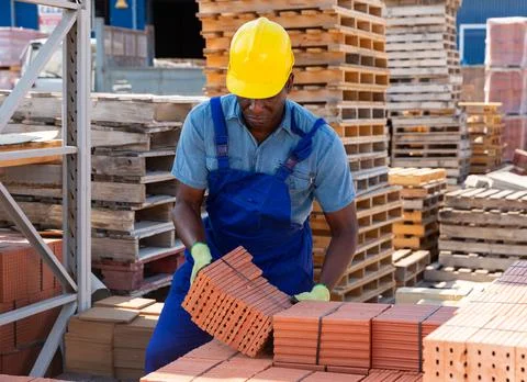 Worker stacking bricks in warehouse of building materials clpseup Stock Photos