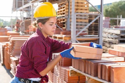 Worker stacking bricks in warehouse of building materials on an open-air site Foto stock