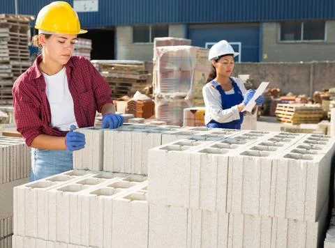 Worker stacking bricks in warehouse of building materials on an open-air site Fotos de archivo