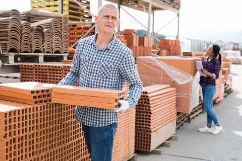 Worker stacking bricks in warehouse of materials Foto stock