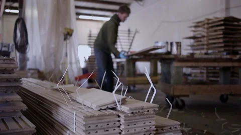 Worker stacking finished hardwood flooring in a factory Stock Footage 335096093