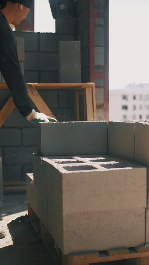 A worker is stacking large concrete blocks at a construction site. Stock Footage 346703538