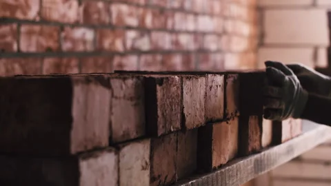 A worker stacks red bricks in a warehouse Stock Footage 251429352