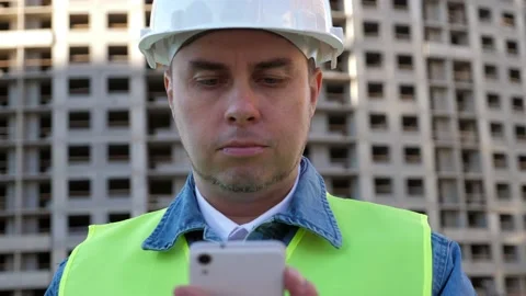 Worker staff in protective helmet using smartphone at construction site Stock Footage 139654548