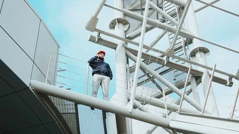 The worker stands on a metal structure and talks on his cell phone Video stock 73470265
