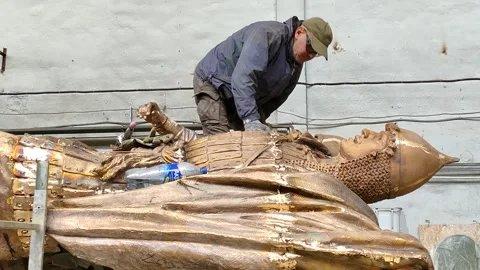 A worker stands on a sculpture and processes a monument to Alexander Nevsky Stock Footage 157781411