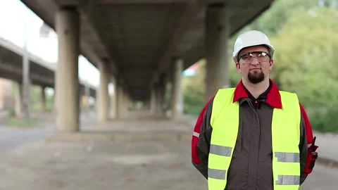 Worker stands under overpass and looks at camera Stock Footage 86130645