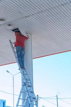 Worker on a stepladder checks or repairs something in a hatch on the ceiling Stock-Fotos