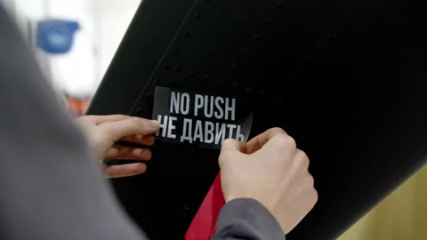 Worker sticks sticker on black surface with the inscription NO PUSH. white Stock Footage 194904811