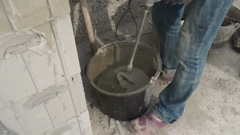Worker stirring cement mortar in a bucket with a mixer Stock Footage 113385384