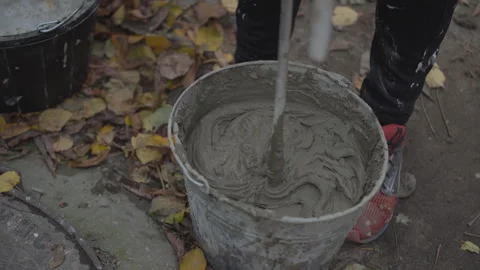 Worker stirs cement with a hand mixer Stock Footage 260642944