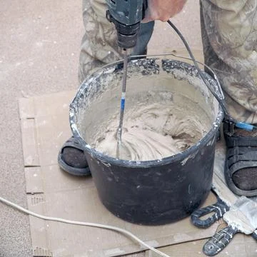 A worker stirs the construction mixture plaster in a bucket with an electric  写真素材