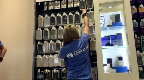 Worker stocking cell phone cover for sale at samsung store Stock Footage 62418889