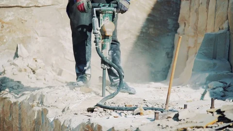 A worker at a stone quarry drills a sandstone block with a jackhammer. Stock Footage 127965959
