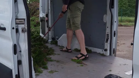 Worker Sweeping Loose Greenery from Cargo Van Floor 库存影片 339187556