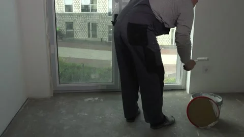 Worker take white paint from bucket with roller and paint window side Stock Footage 130511515