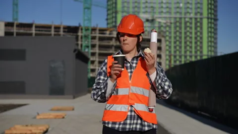 Worker takes a break, enjoying coffee and studying important project plans Stock Footage 311859861