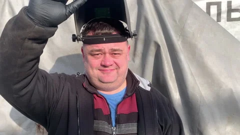 The worker takes off his welder's mask and smiles. Stock Footage 304162023