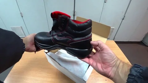 Worker takes out of the box and looks at the protective shoes. Video stock 82470313