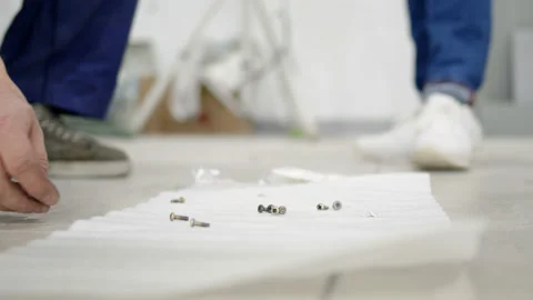 Worker takes screw from floor, which lies on paper napkin. Close up view of Stock Footage 194904701