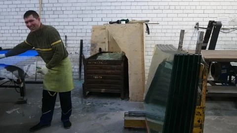 The worker takes the sheet of glass from the table and puts on the counter. Stock-Footage 122129493