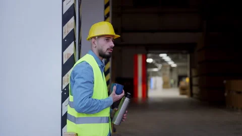 Worker taking break from work, drinking coffee, standing on loading dock Stock Footage 262100843