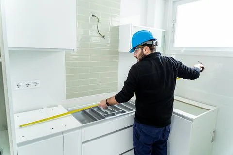 Worker taking measurement of a kitchen that he is assembling Stock Photos