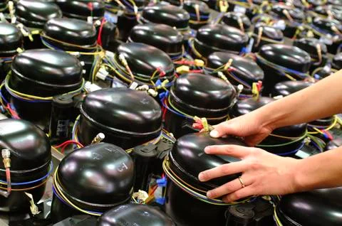 Worker taking a refrigerator compressor with his hands Stock Photos