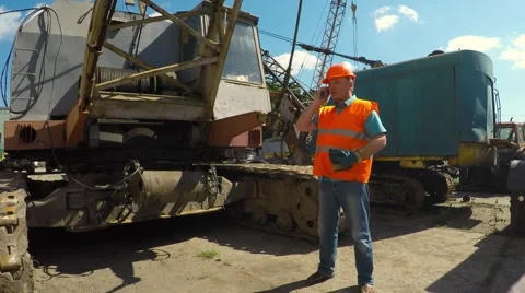 Worker talking on the phone about a caterpillar crane. Video stock 52251884