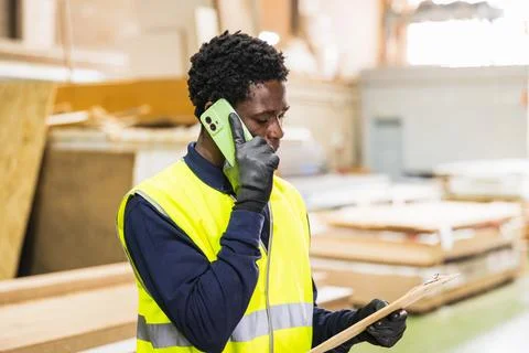 Worker talking on phone checking lumberyard inventory Stock Photos