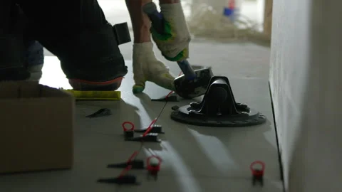 Worker tapping floor tile with rubber mallet during installation Stock-Footage 344473780