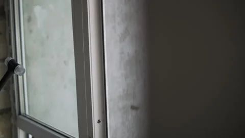 Worker tapping window frame with rubber mallet during glass installation Stock Footage 324840213