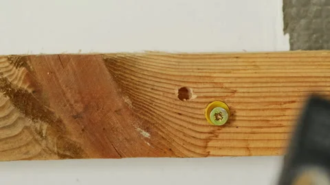 Worker taps with hammer installing nail into wall anchor Video stock 304404395