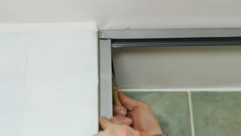 Worker taps with hammer securing metal construction to wall Stock Footage 304405449