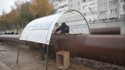 Worker taps metal pipe with hammer under plastic canopy Vídeo Stock 313828899