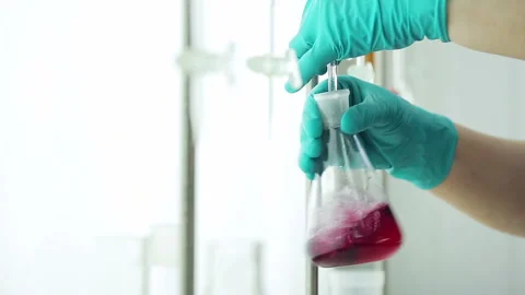 Worker of the testing center at oil depot mixes the liquid in glass beaker, chan Video stock 199487277