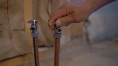 Worker testing a new residential water supply system by opening a valve to Stockbeeldmateriaal 346802040