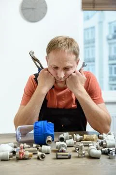 The worker is thinking and looking at the elements of the plumbing. Stock Photos