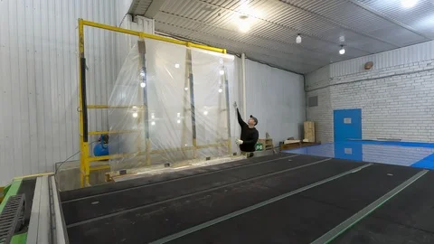 Worker throws the sheet of glass from the rack on the CNC cutting table. Stock-Footage 123950629