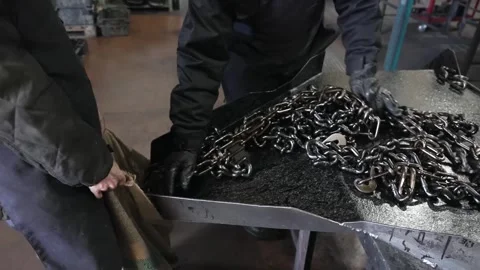 Worker ties a bundle of finished chains into a burlap sack using gloved hands Stock Footage 339123494