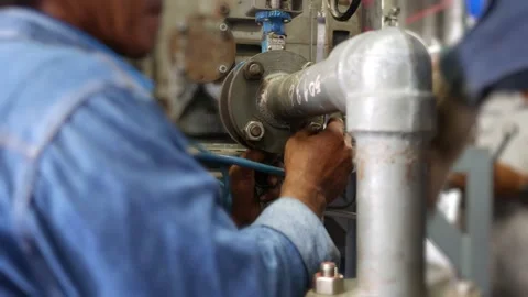 Worker tighten and fix bolt to a machine in refinery factory Stock Footage 153795533