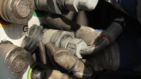 Worker tightening hydraulic connection while wearing protective gloves Stock Footage 345081196