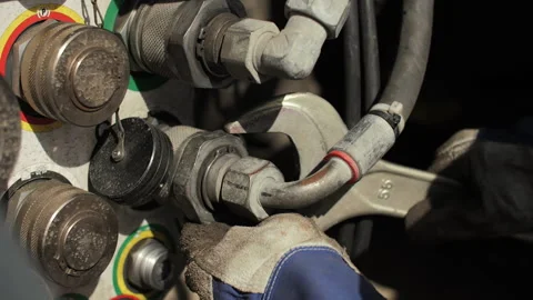 Worker tightening hydraulic coupling with wrench on heavy transport platform Stock Footage 345081258