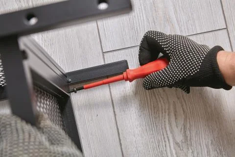 Worker is tightening screws while assembling flat pack furniture with metal f Stock Photos