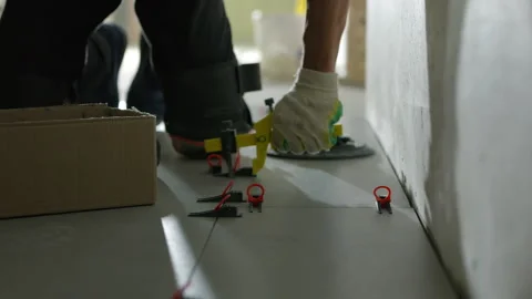 Worker tightening tile leveling clips during floor installation Stock Footage 344473047