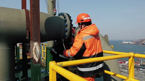 A worker tightens a large nut on a newly constructed roof in the port. Stock Footage 231215302